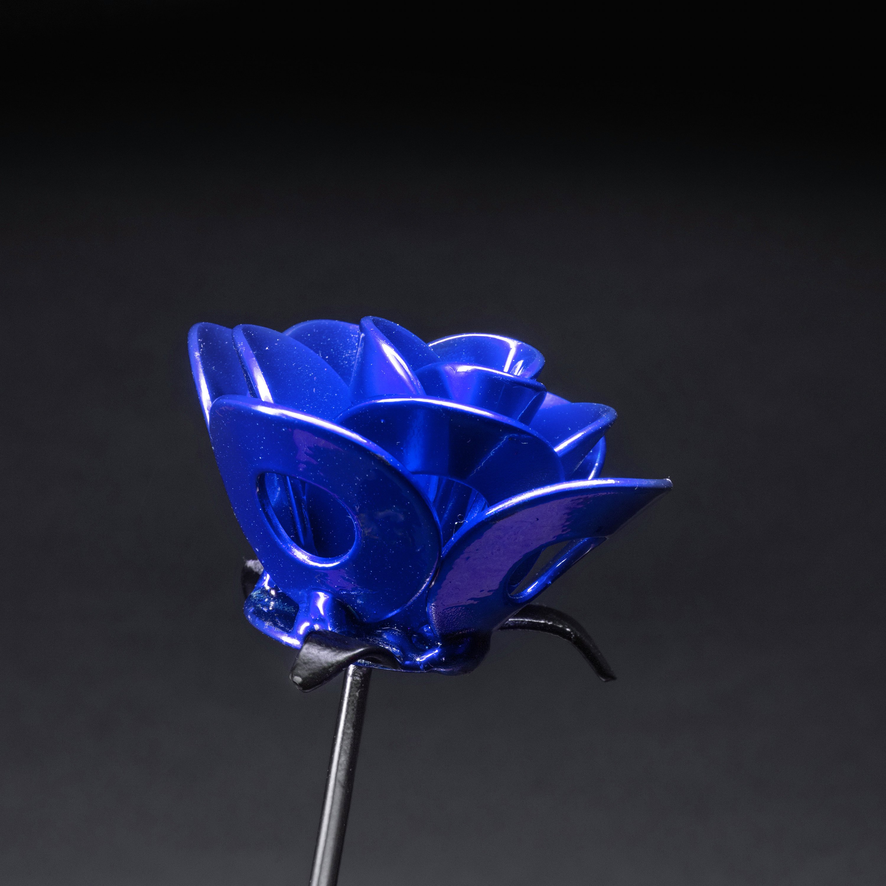 A handcrafted blue and black metal rose made from recycled materials, showcasing intricate welded details and a lustrous finish.