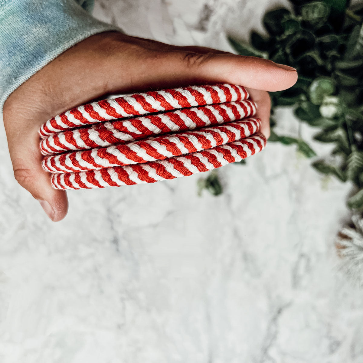 Set of four blue braided coasters with a candy cane stripe pattern, perfect for protecting surfaces and adding festive decor.