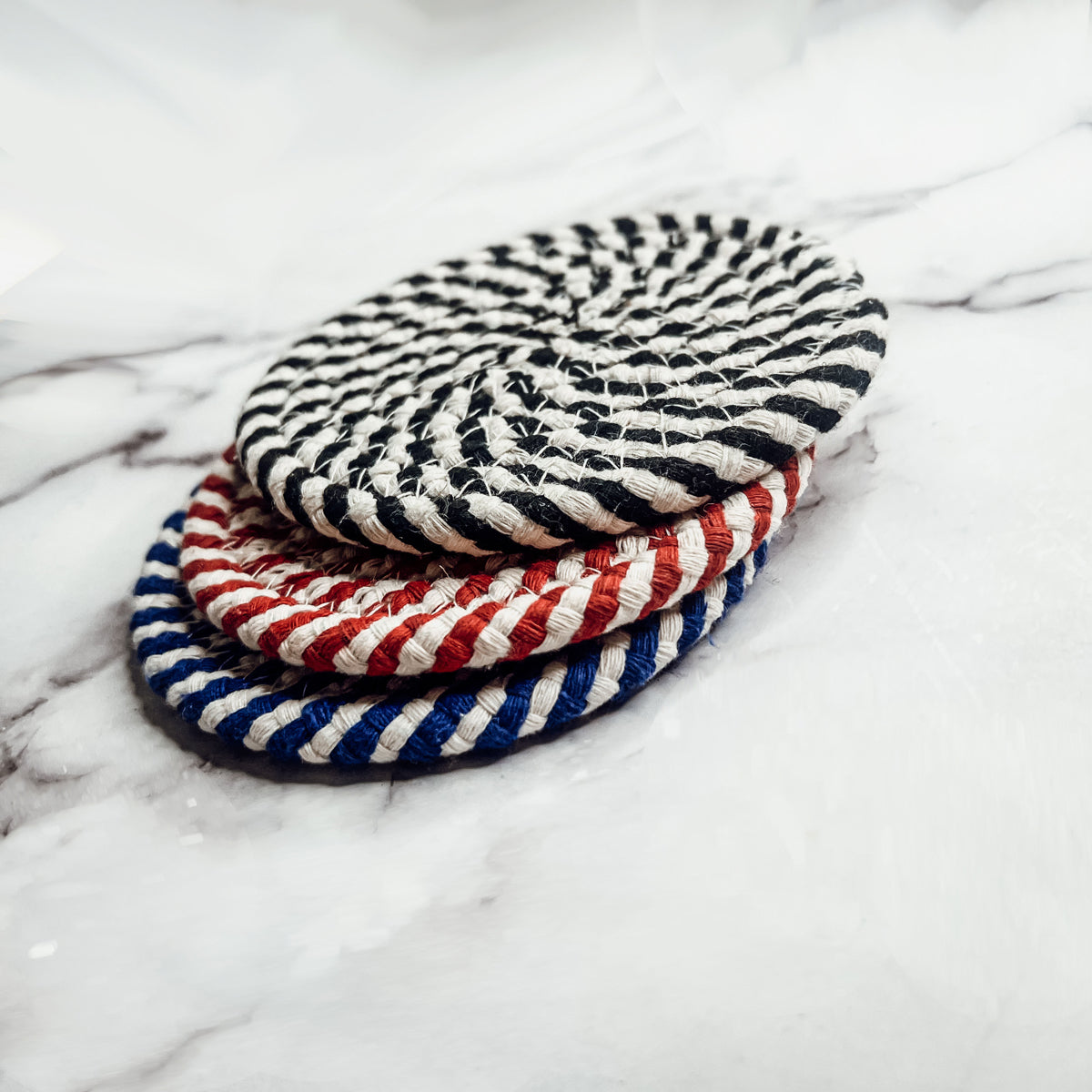 Set of four blue braided coasters with a candy cane stripe pattern, perfect for protecting surfaces and adding festive decor.