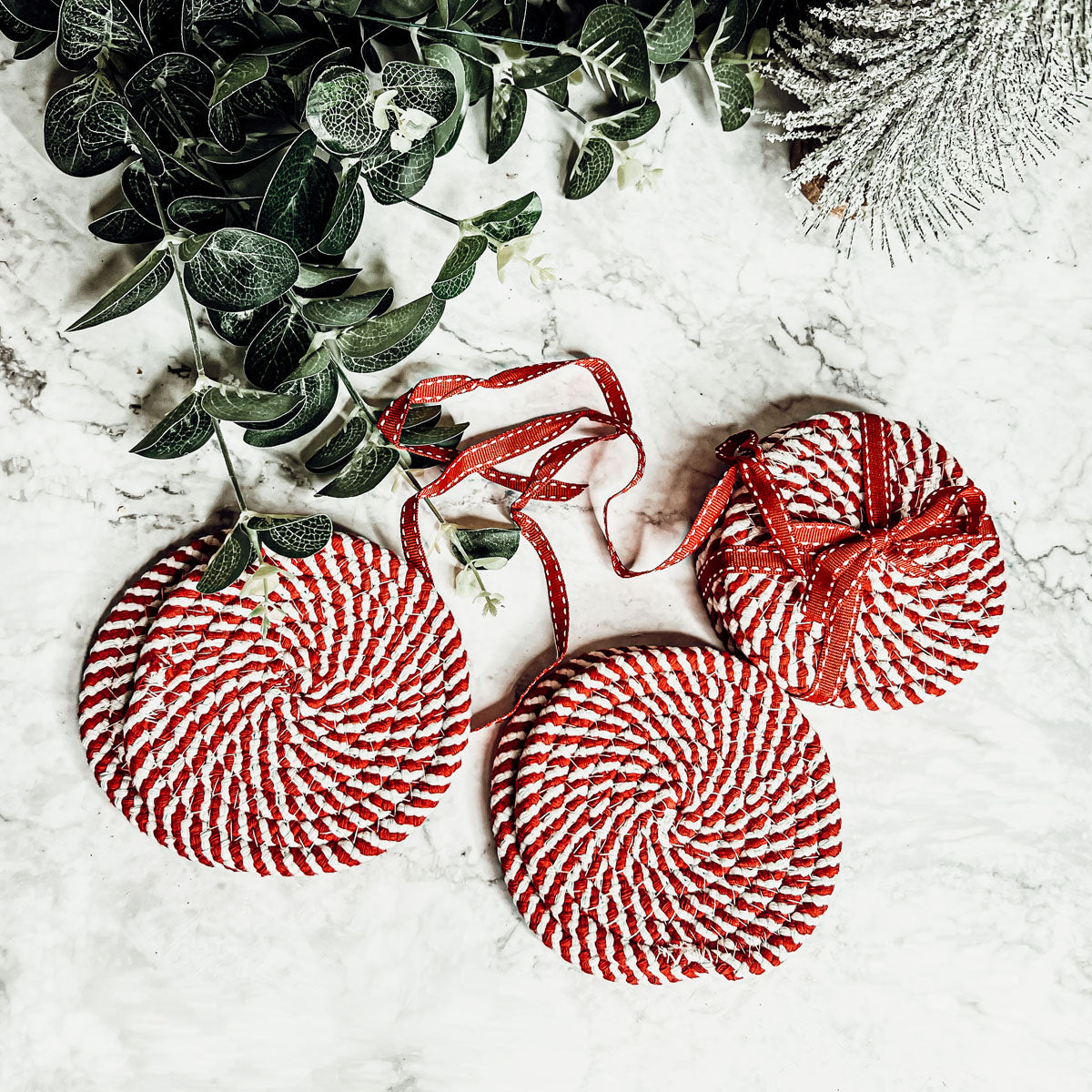 Set of four blue braided coasters with a candy cane stripe pattern, perfect for protecting surfaces and adding festive decor.