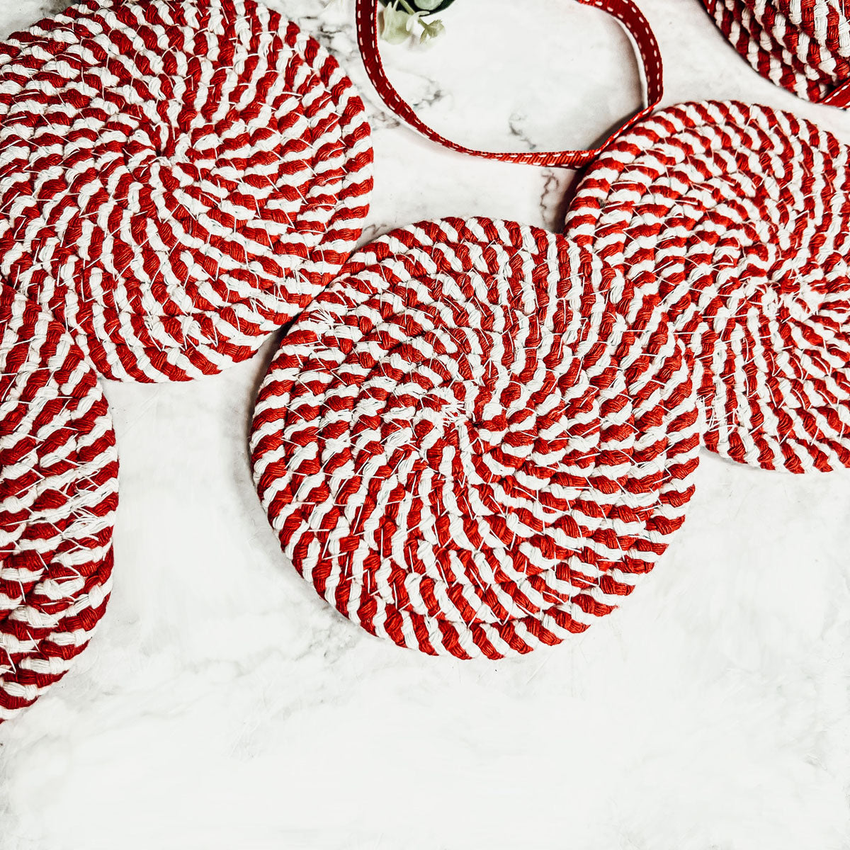 Set of four blue braided coasters with a candy cane stripe pattern, perfect for protecting surfaces and adding festive decor.