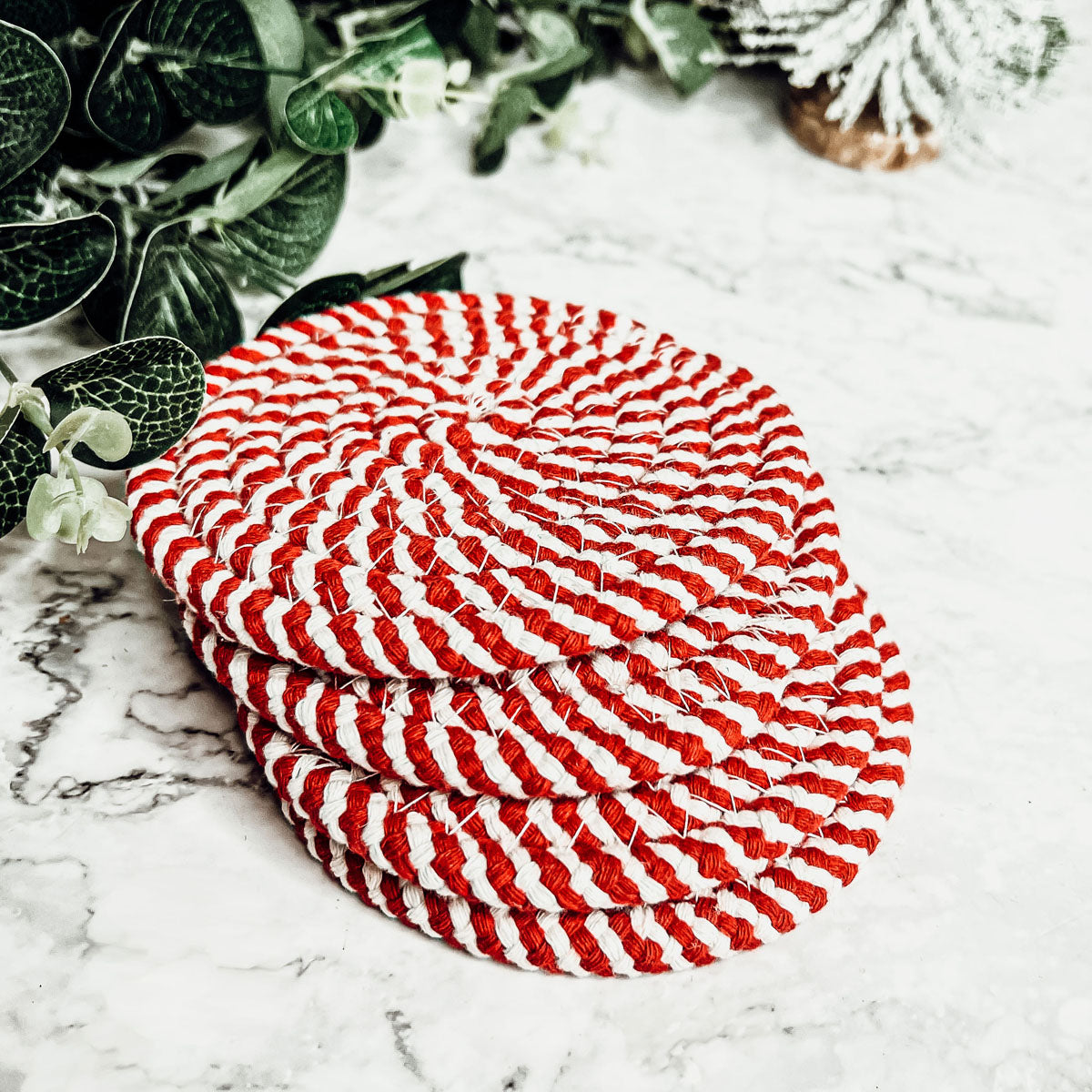 Set of four blue braided coasters with a candy cane stripe pattern, perfect for protecting surfaces and adding festive decor.