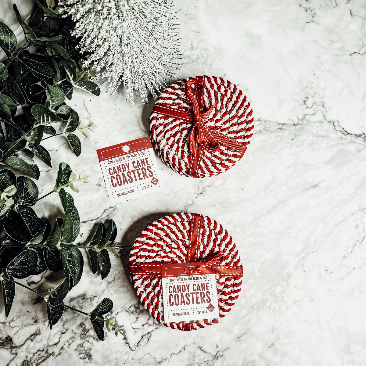 Set of four blue braided coasters with a candy cane stripe pattern, perfect for protecting surfaces and adding festive decor.