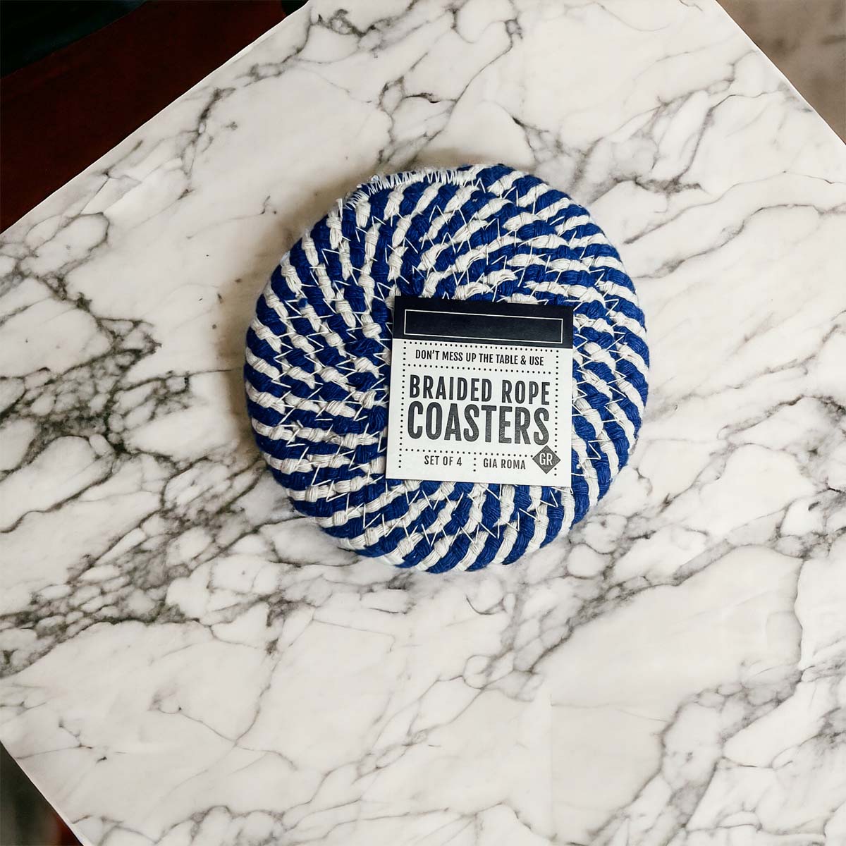 Set of four blue braided coasters with a candy cane stripe pattern, perfect for protecting surfaces and adding festive decor.