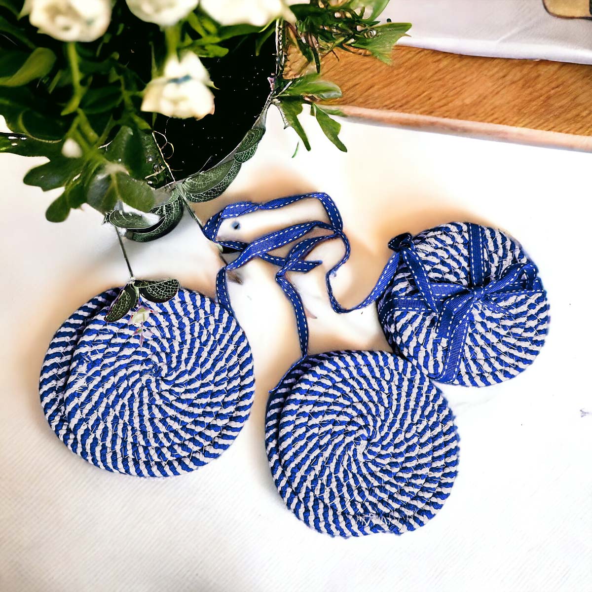 Set of four blue braided coasters with a candy cane stripe pattern, perfect for protecting surfaces and adding festive decor.