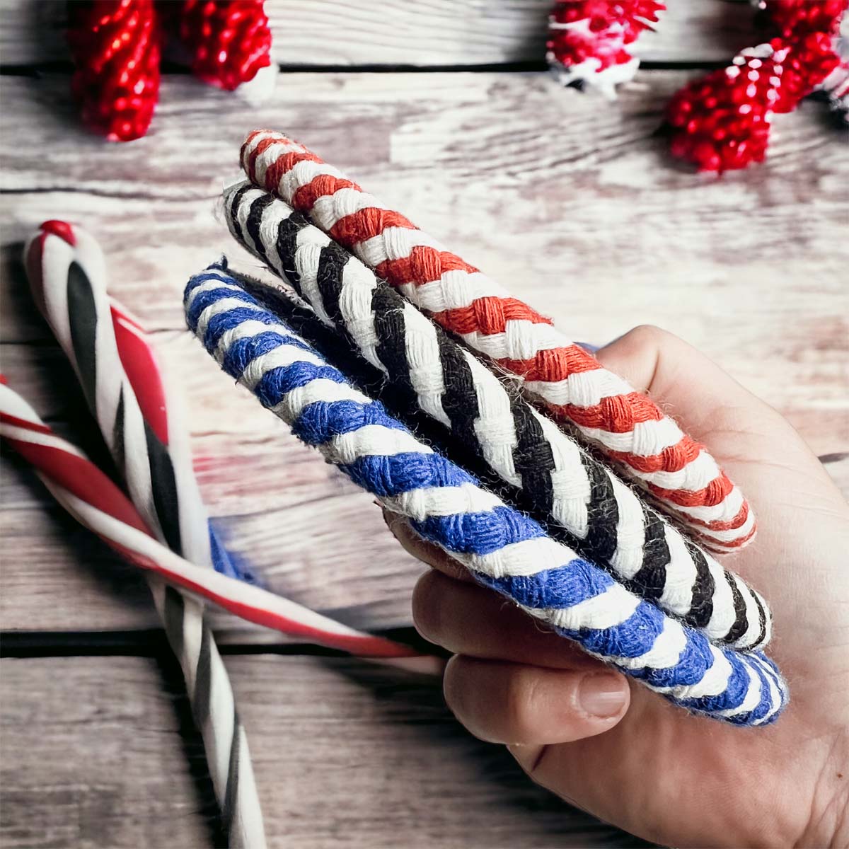 Set of four blue braided coasters with a candy cane stripe pattern, perfect for protecting surfaces and adding festive decor.