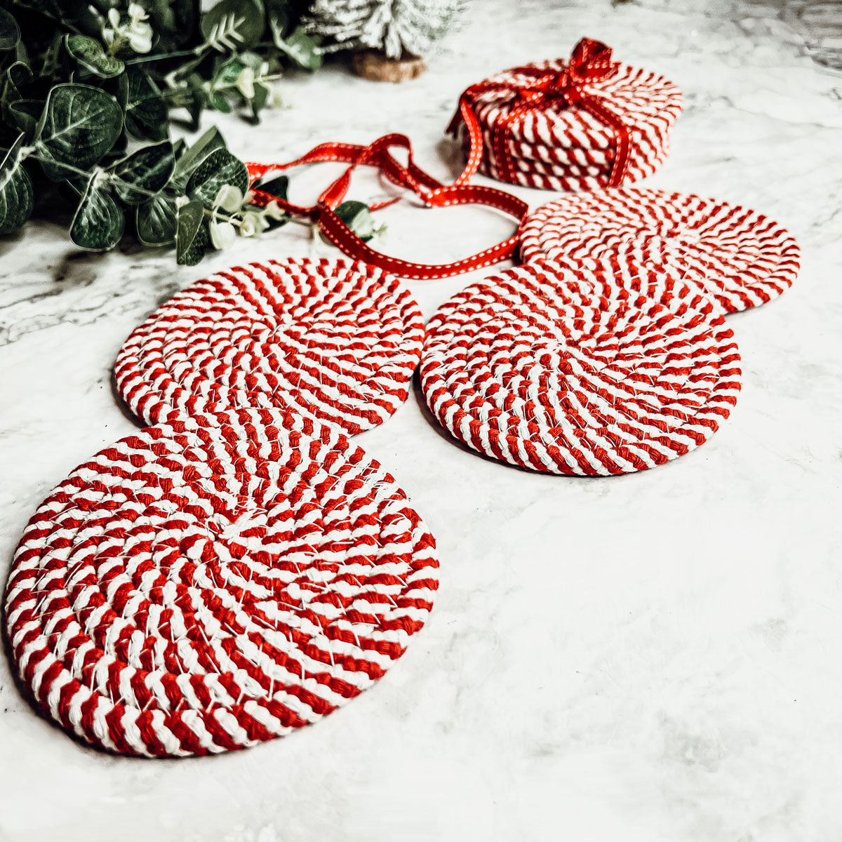 Set of four blue braided coasters with a candy cane stripe pattern, perfect for protecting surfaces and adding festive decor.