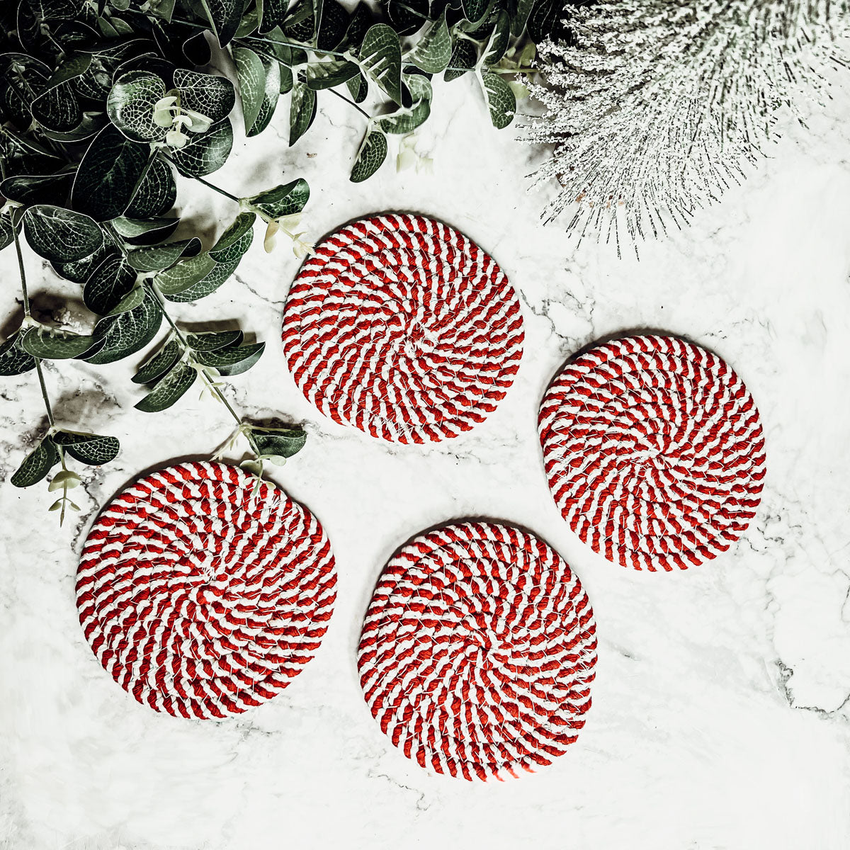 Set of four blue braided coasters with a candy cane stripe pattern, perfect for protecting surfaces and adding festive decor.