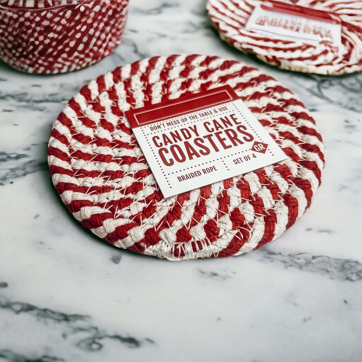 Set of four blue braided coasters with a candy cane stripe pattern, perfect for protecting surfaces and adding festive decor.