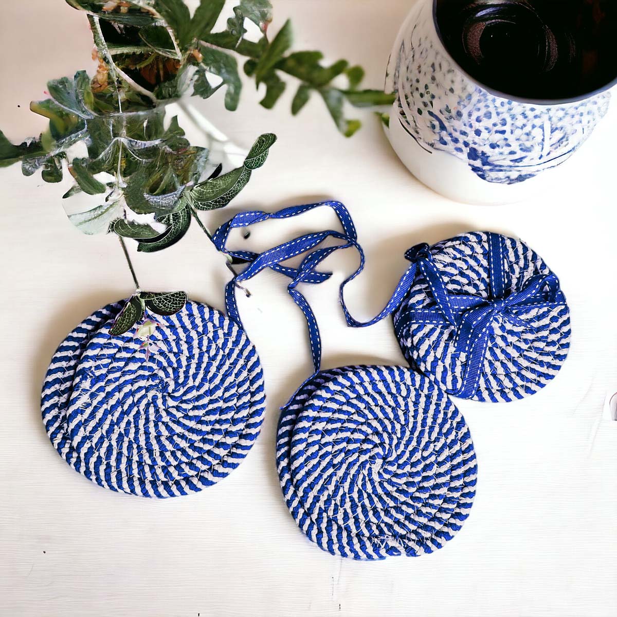 Set of four blue braided coasters with a candy cane stripe pattern, perfect for protecting surfaces and adding festive decor.