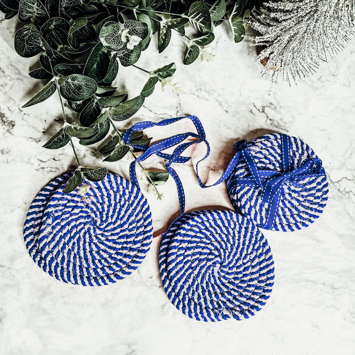 Set of four blue braided coasters with a candy cane stripe pattern, perfect for protecting surfaces and adding festive decor.