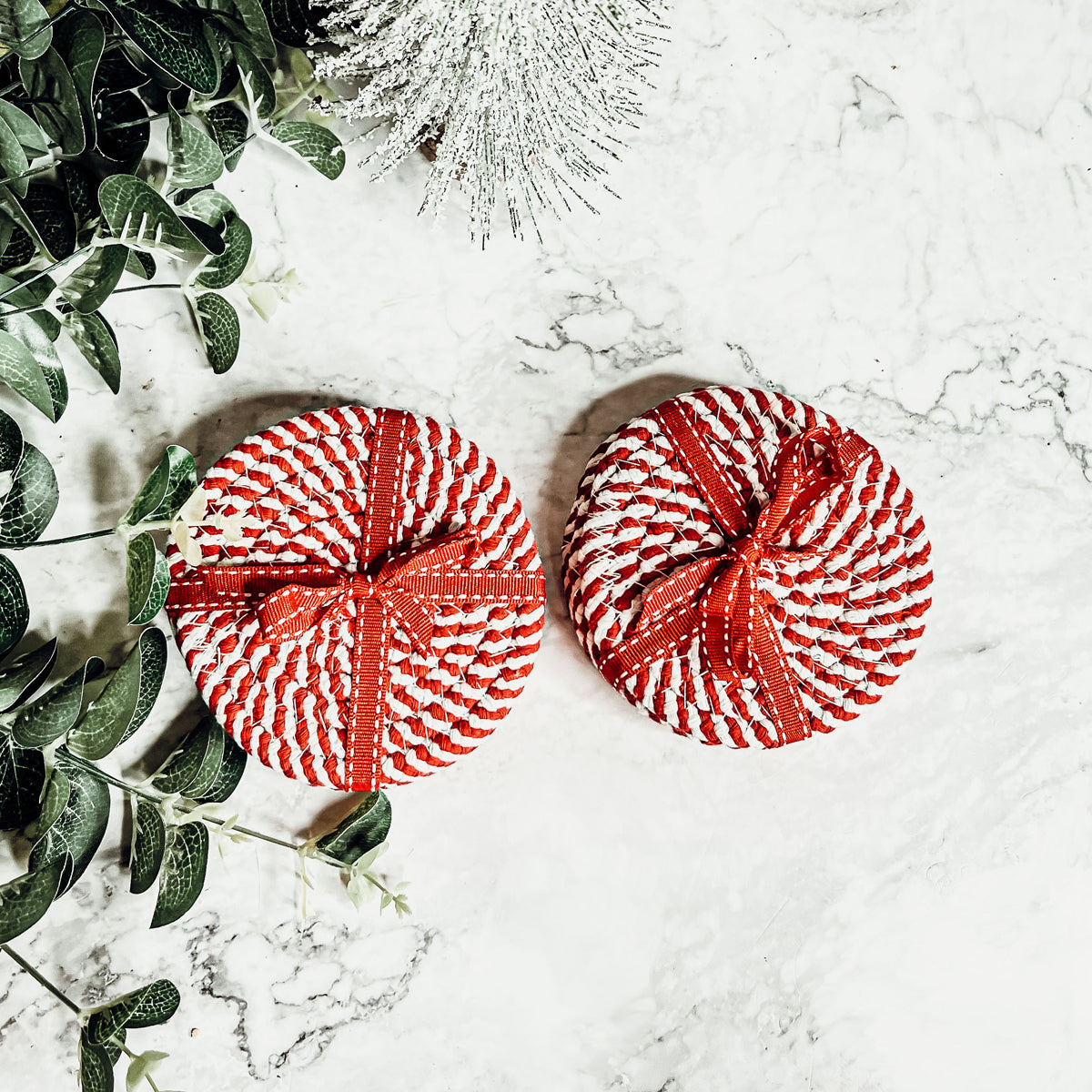 Set of four blue braided coasters with a candy cane stripe pattern, perfect for protecting surfaces and adding festive decor.