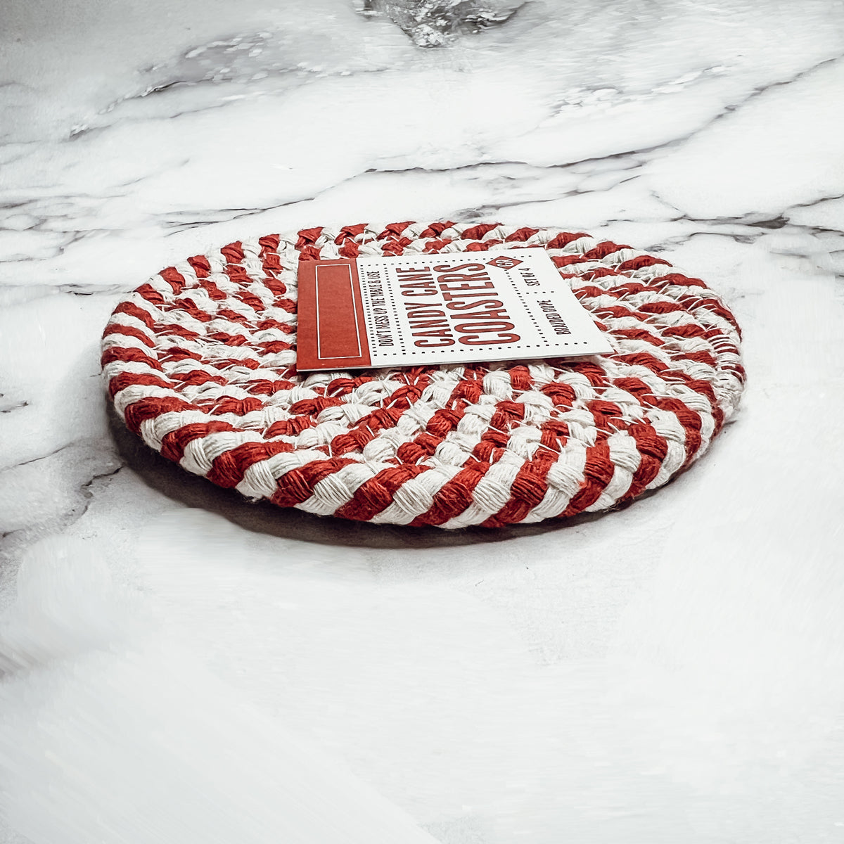 Set of four blue braided coasters with a candy cane stripe pattern, perfect for protecting surfaces and adding festive decor.