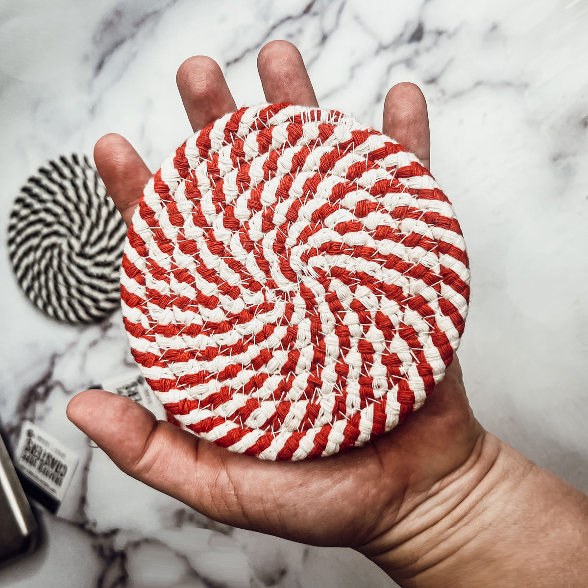 Set of four blue braided coasters with a candy cane stripe pattern, perfect for protecting surfaces and adding festive decor.