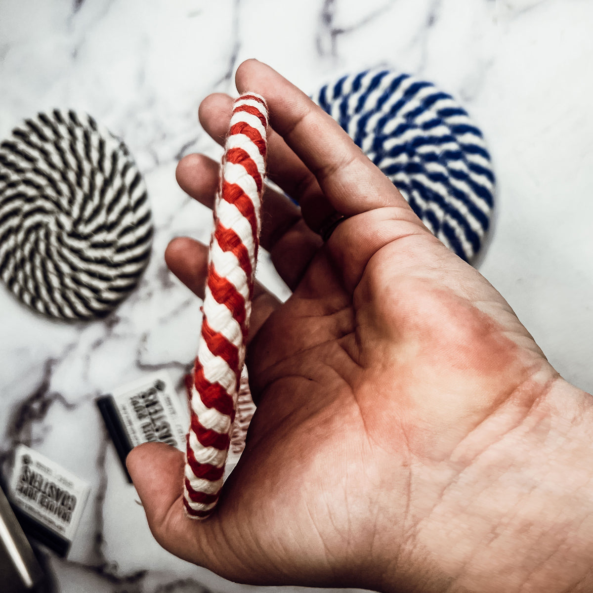 Set of four blue braided coasters with a candy cane stripe pattern, perfect for protecting surfaces and adding festive decor.