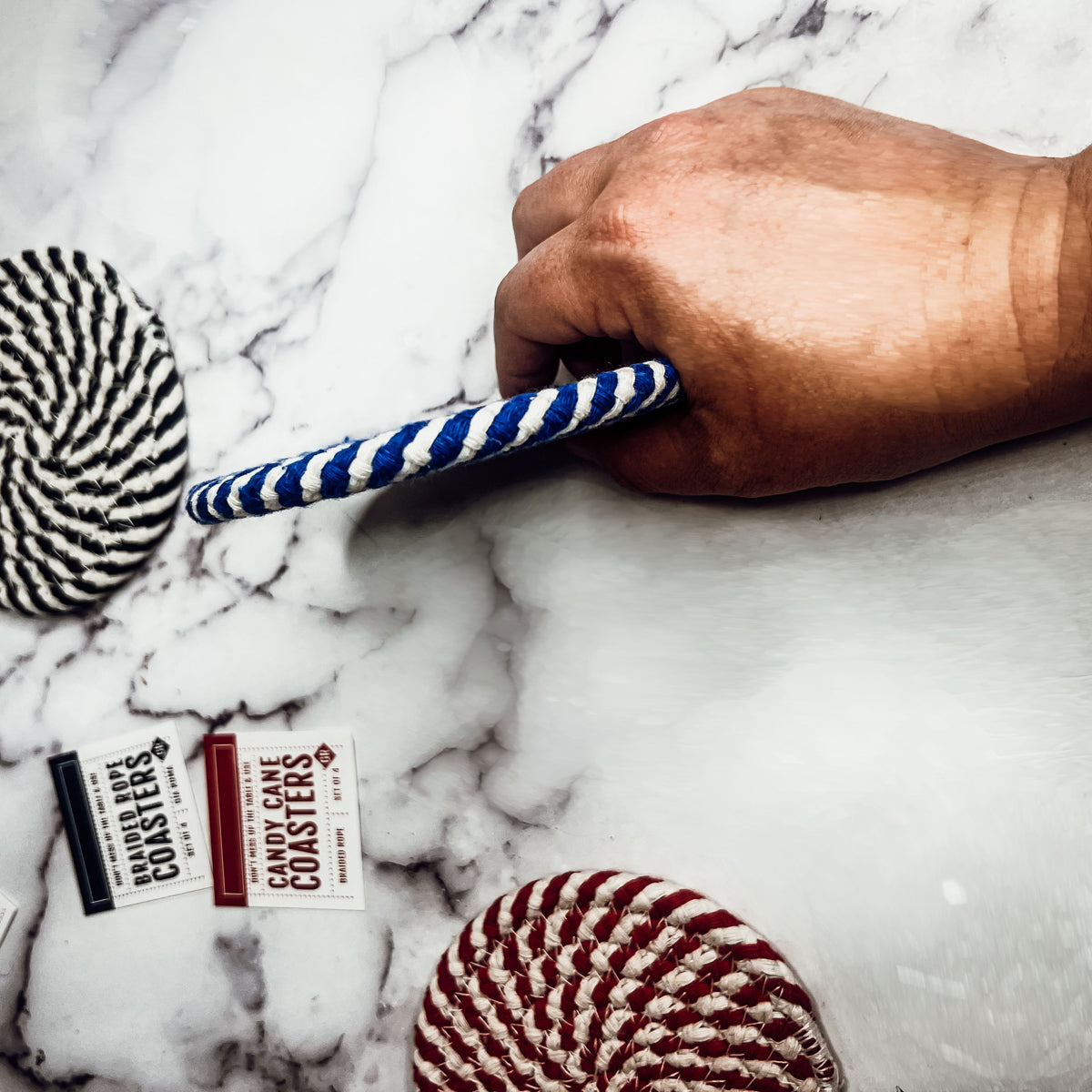 Set of four blue braided coasters with a candy cane stripe pattern, perfect for protecting surfaces and adding festive decor.