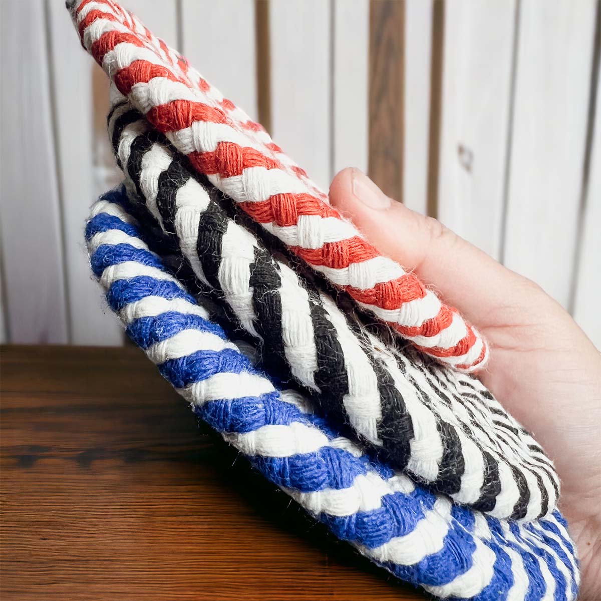 Set of four blue braided coasters with a candy cane stripe pattern, perfect for protecting surfaces and adding festive decor.