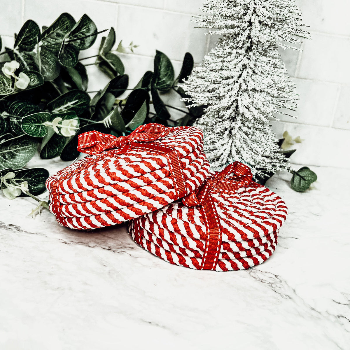 Set of four blue braided coasters with a candy cane stripe pattern, perfect for protecting surfaces and adding festive decor.