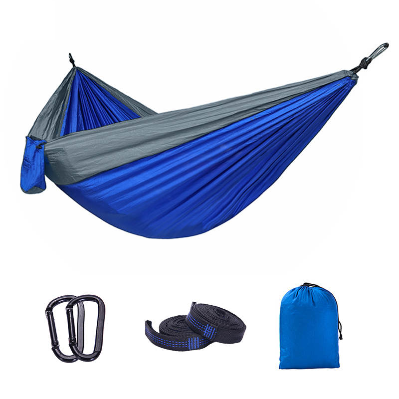 Blue and grey camping hammock set up between two trees, showcasing its spacious design and durable straps.