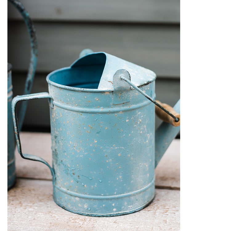 A vibrant turquoise blue rustic watering can made of metal and wood, featuring a charming design suitable for indoor and outdoor use.