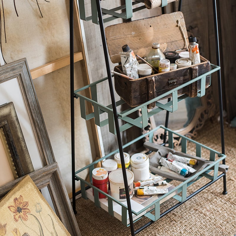 A rustic blue metal shelf with three tiered baskets, showcasing a vintage design perfect for home decor.