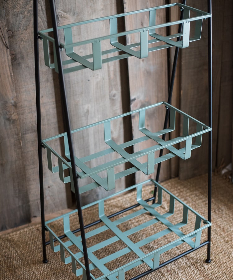 A rustic blue metal shelf with three tiered baskets, showcasing a vintage design perfect for home decor.