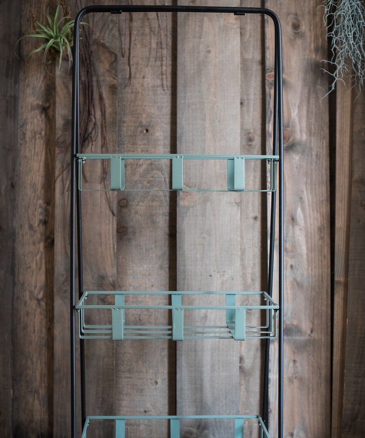 A rustic blue metal shelf with three tiered baskets, showcasing a vintage design perfect for home decor.