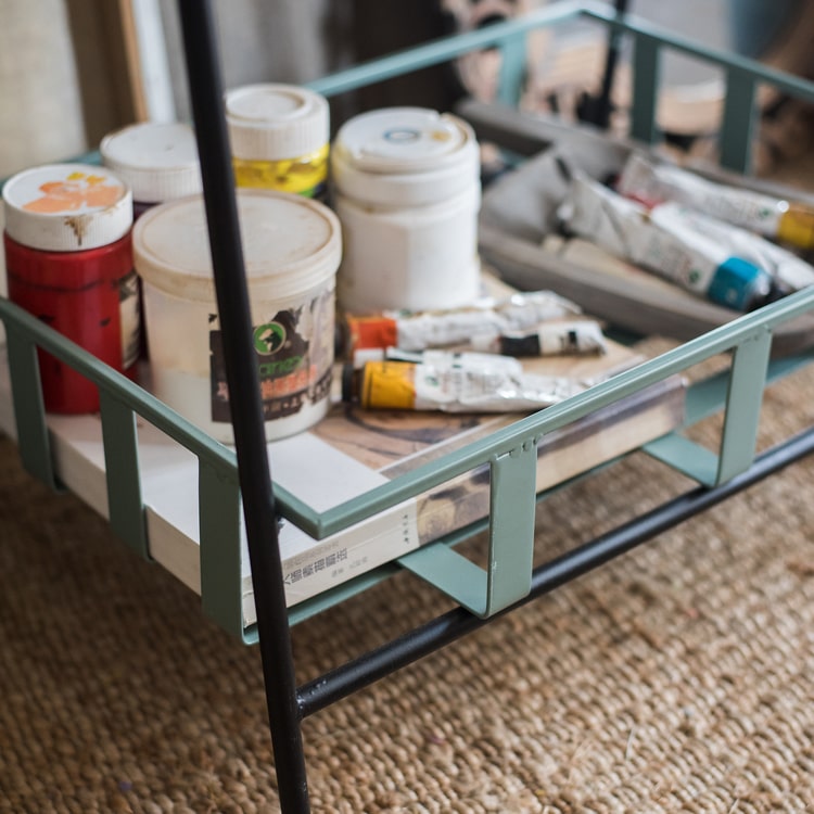 A rustic blue metal shelf with three tiered baskets, showcasing a vintage design perfect for home decor.