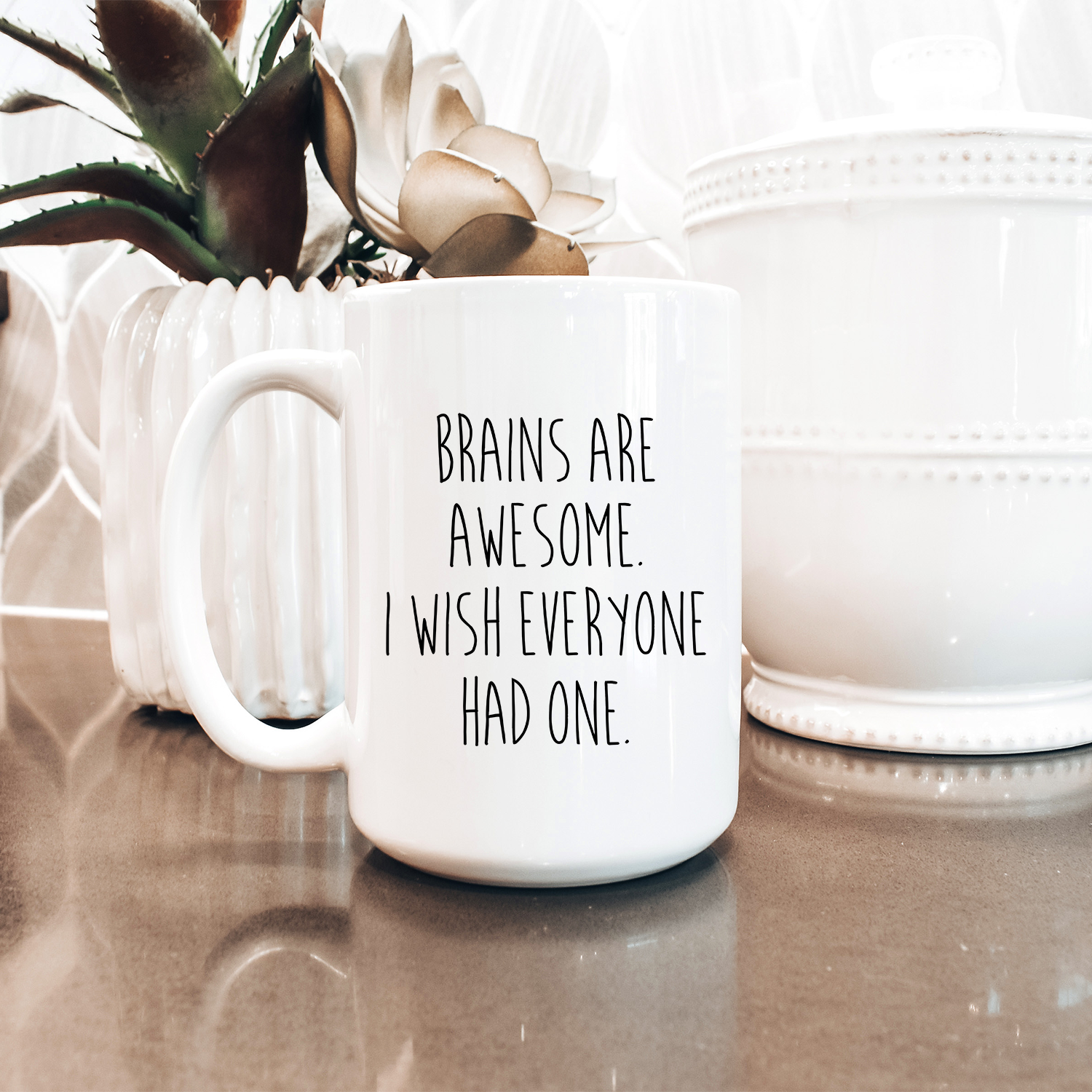 A glossy white ceramic mug with a vibrant print saying 'Brains are Awesome', perfect for coffee or tea.