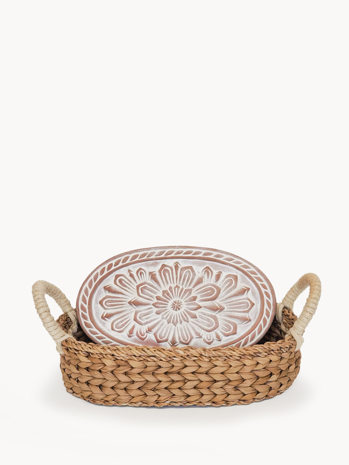 A beautifully crafted Flower Bread Warmer made of terracotta, placed inside a handwoven seagrass basket, showcasing intricate flower engravings.