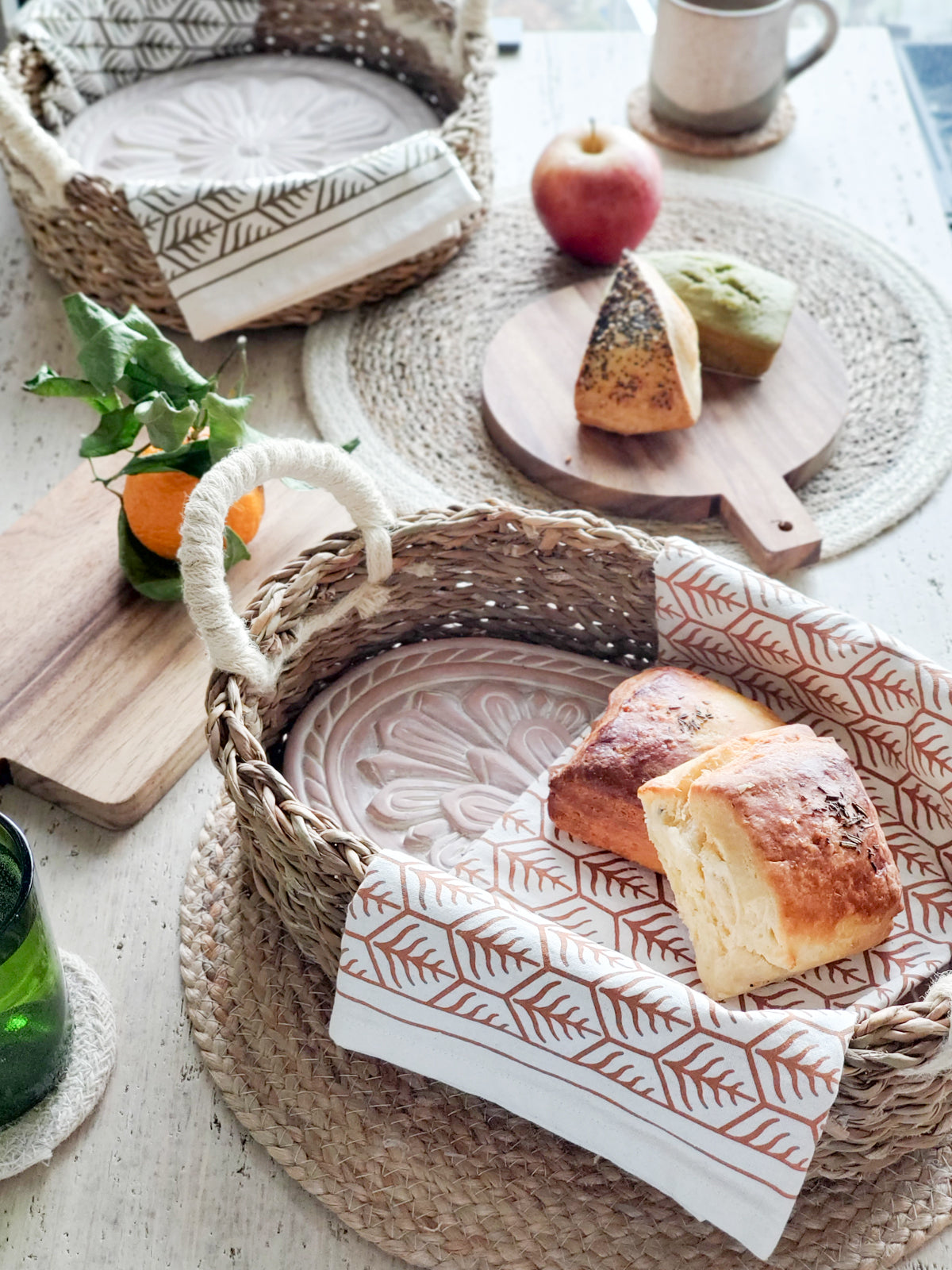 A beautifully crafted Flower Bread Warmer made of terracotta, placed inside a handwoven seagrass basket, showcasing intricate flower engravings.