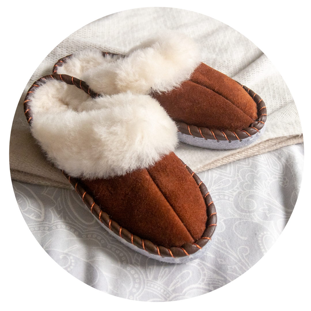 A pair of elegant brown shearling sheepskin mules, showcasing their soft texture and genuine leather detailing, perfect for comfortable wear.