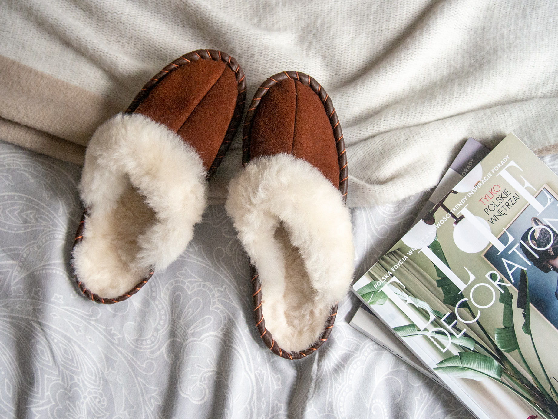 A pair of elegant brown shearling sheepskin mules, showcasing their soft texture and genuine leather detailing, perfect for comfortable wear.