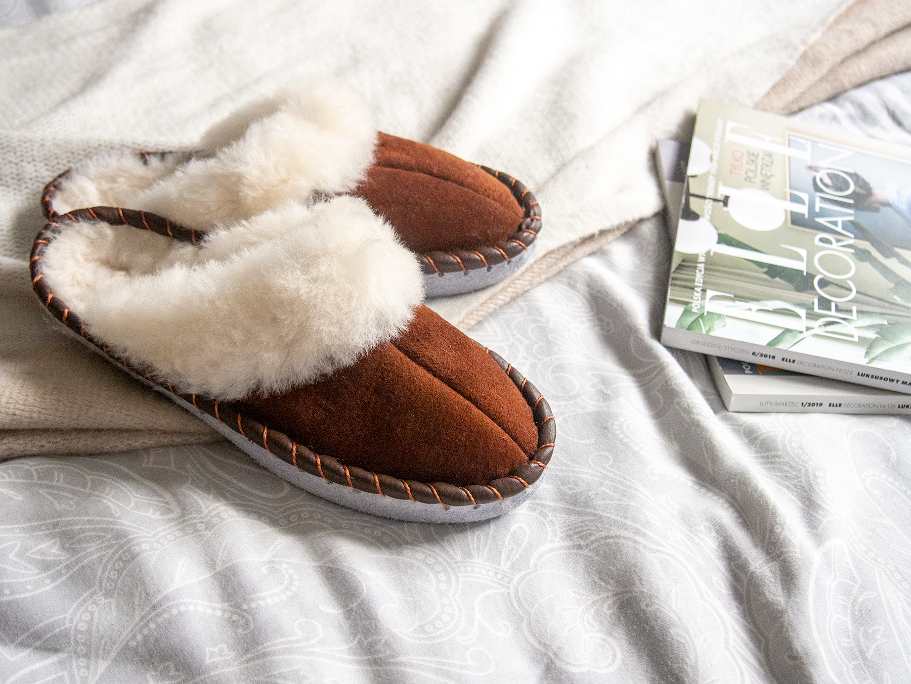 A pair of elegant brown shearling sheepskin mules, showcasing their soft texture and genuine leather detailing, perfect for comfortable wear.