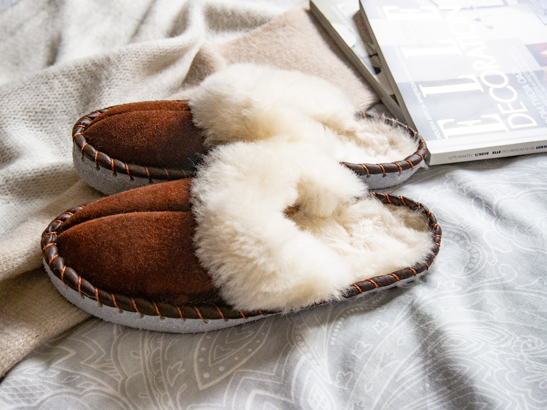 A pair of elegant brown shearling sheepskin mules, showcasing their soft texture and genuine leather detailing, perfect for comfortable wear.