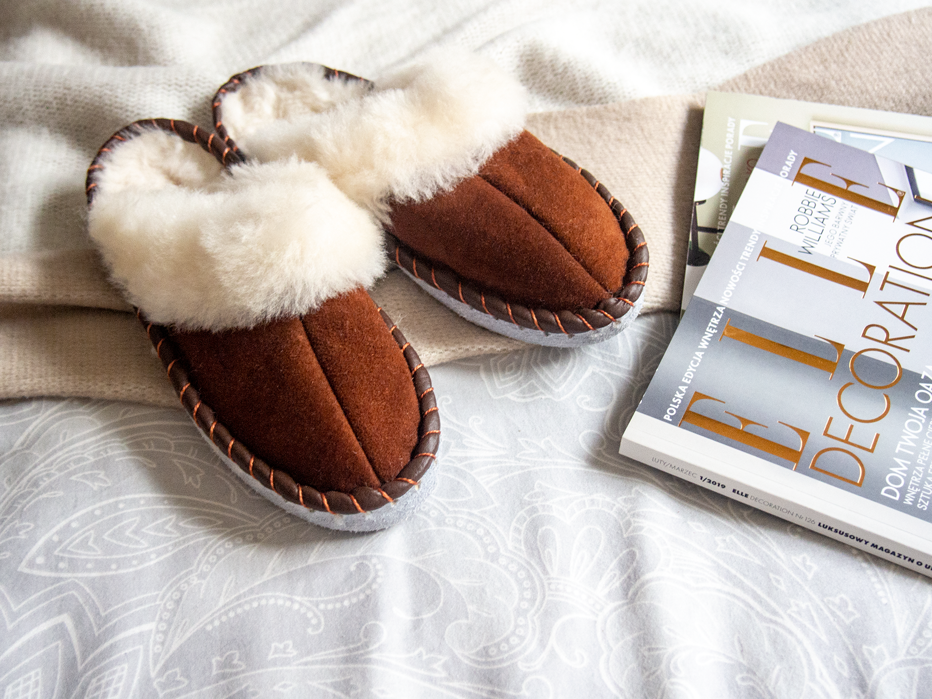 A pair of elegant brown shearling sheepskin mules, showcasing their soft texture and genuine leather detailing, perfect for comfortable wear.