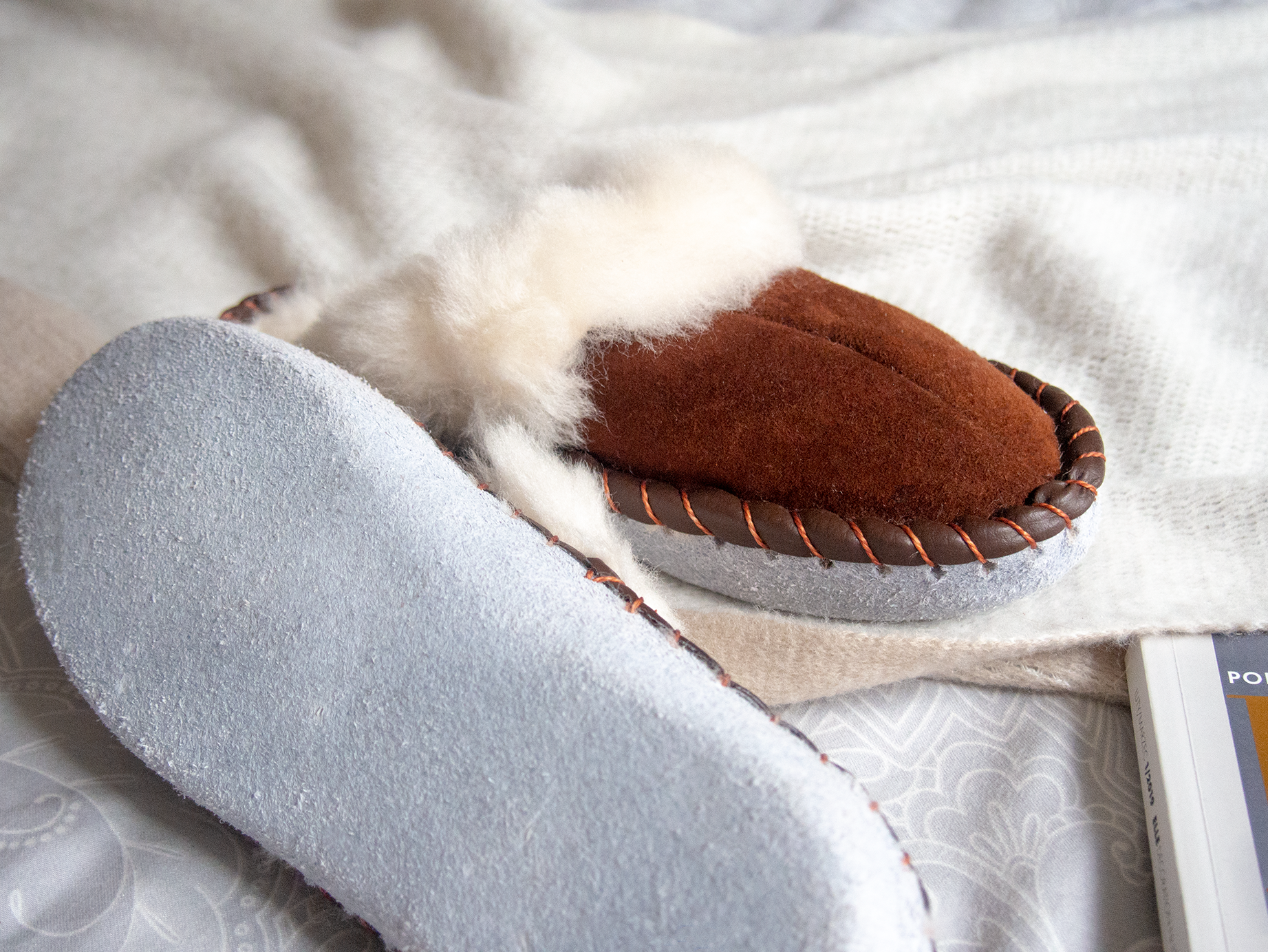 A pair of elegant brown shearling sheepskin mules, showcasing their soft texture and genuine leather detailing, perfect for comfortable wear.