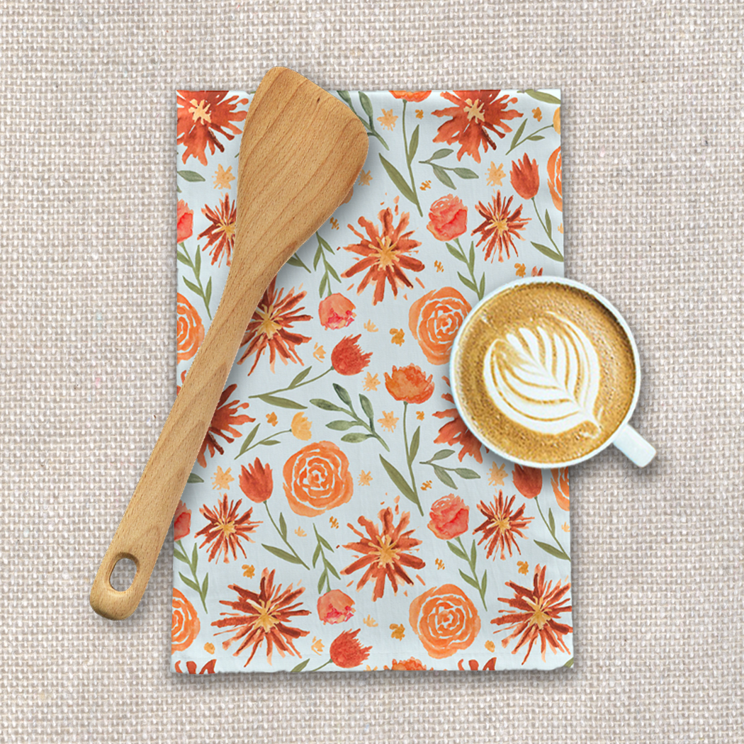 Burnt orange tea towel featuring a vibrant floral burst design, made from durable cotton twill, perfect for kitchen use.