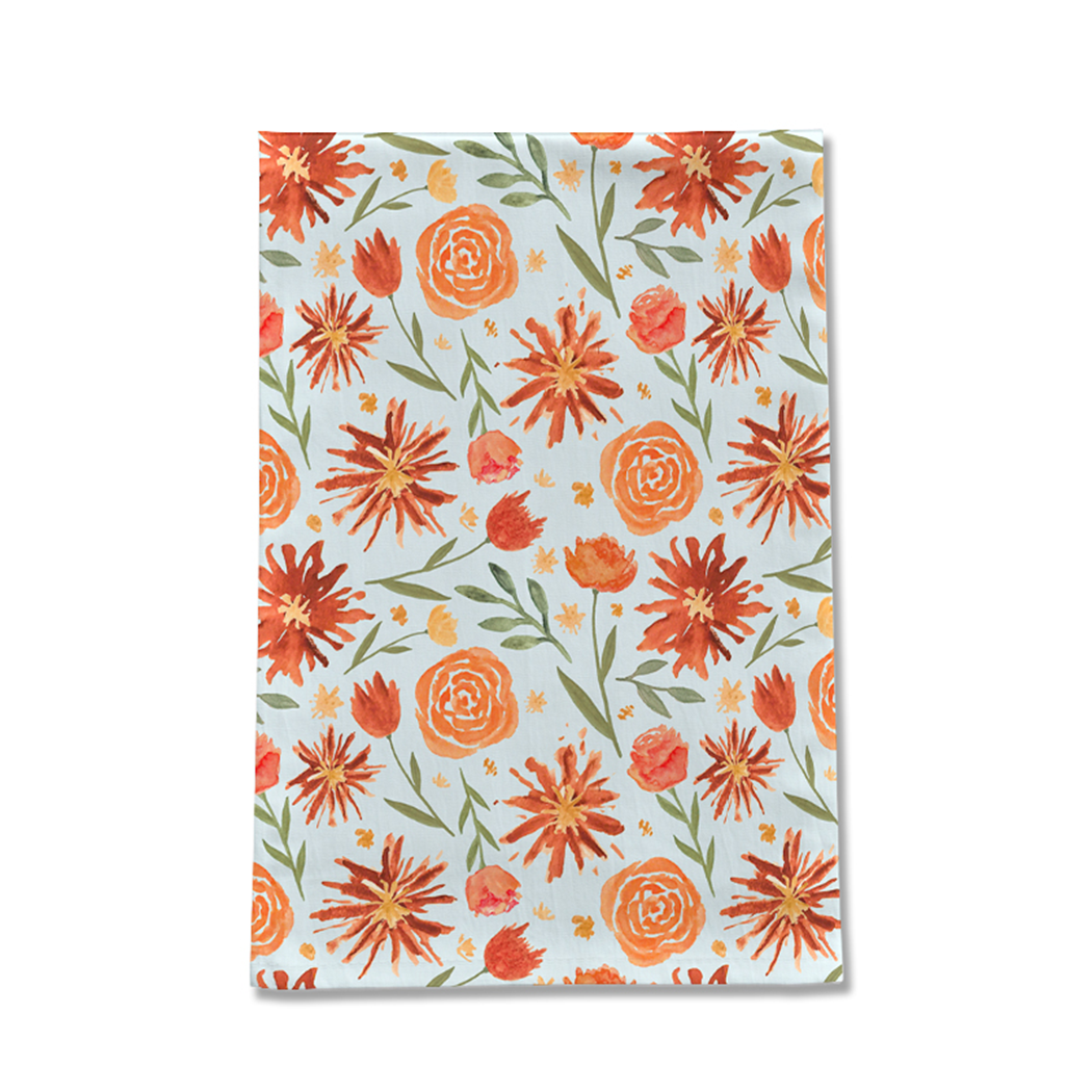 Burnt orange tea towel featuring a vibrant floral burst design, made from durable cotton twill, perfect for kitchen use.