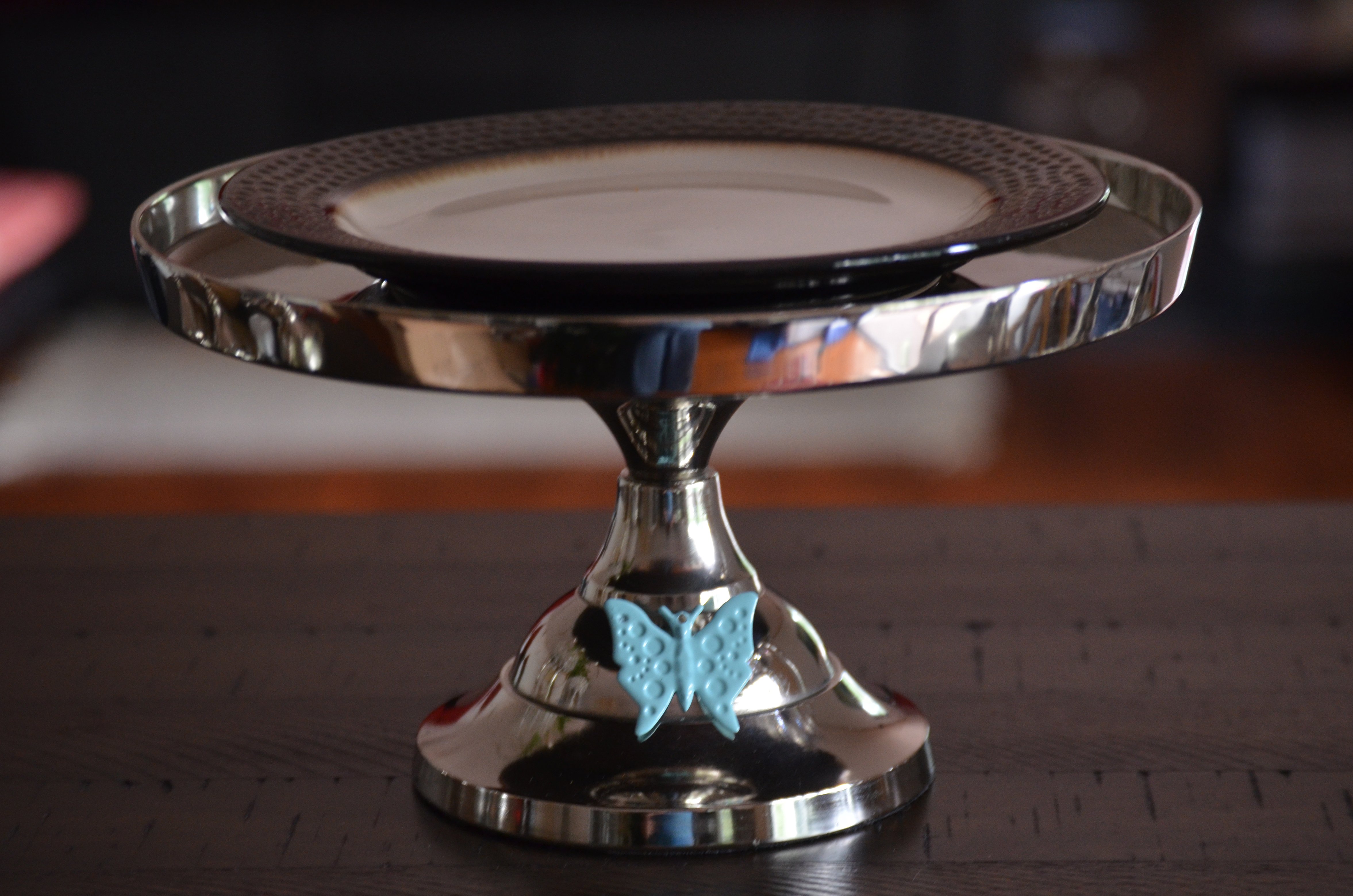 Elegant 10-inch cake stand featuring a turquoise butterfly design, handcrafted from aluminum with a silver finish, perfect for displaying cakes and desserts.