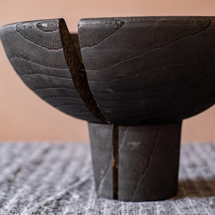 A stylish Carbonized Wood Footed Bowl with a fluted pedestal, showcasing a smoky charcoal color and intricate wood grain patterns.