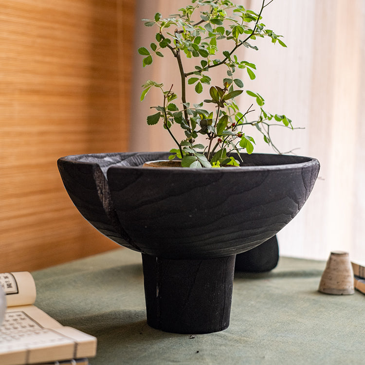 A stylish Carbonized Wood Footed Bowl with a fluted pedestal, showcasing a smoky charcoal color and intricate wood grain patterns.