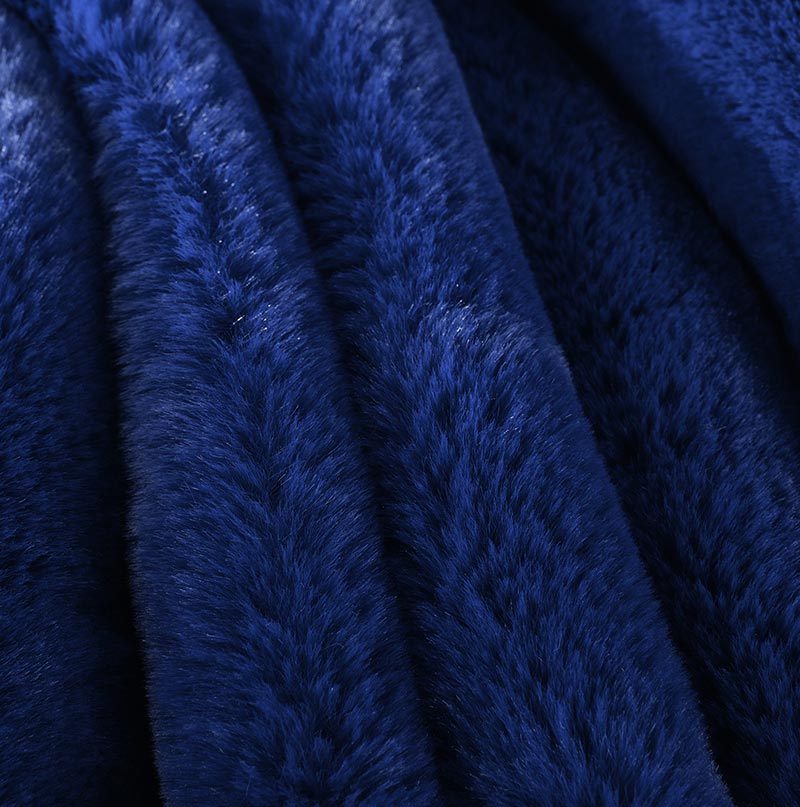 Cassilda Luxury Navy Blue Chinchilla Faux Fur Throw Blanket draped elegantly on a sofa, showcasing its plush texture and rich color.