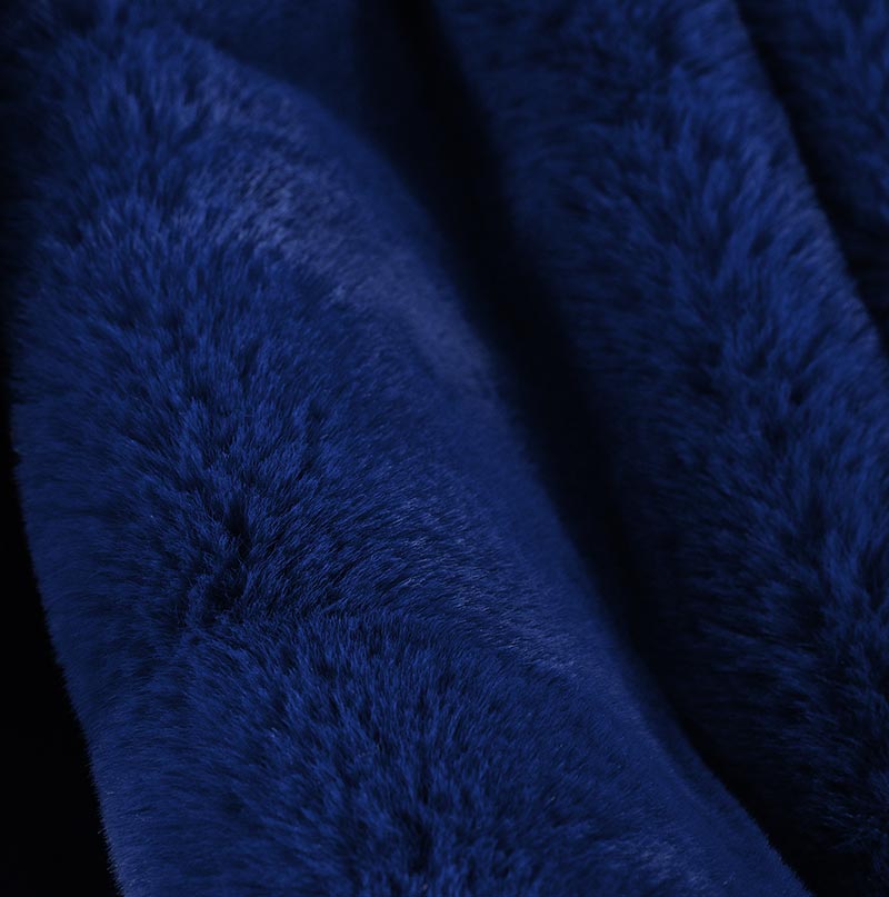 Cassilda Luxury Navy Blue Chinchilla Faux Fur Throw Blanket draped elegantly on a sofa, showcasing its plush texture and rich color.