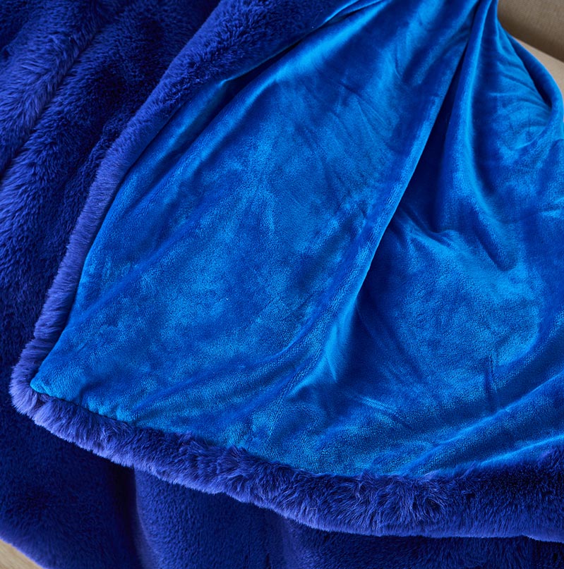 Cassilda Luxury Navy Blue Chinchilla Faux Fur Throw Blanket draped elegantly on a sofa, showcasing its plush texture and rich color.