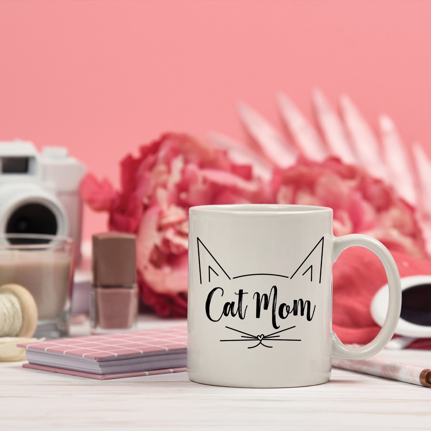 A glossy white ceramic mug with 'Cat Mom' printed in vibrant colors, perfect for coffee or tea.