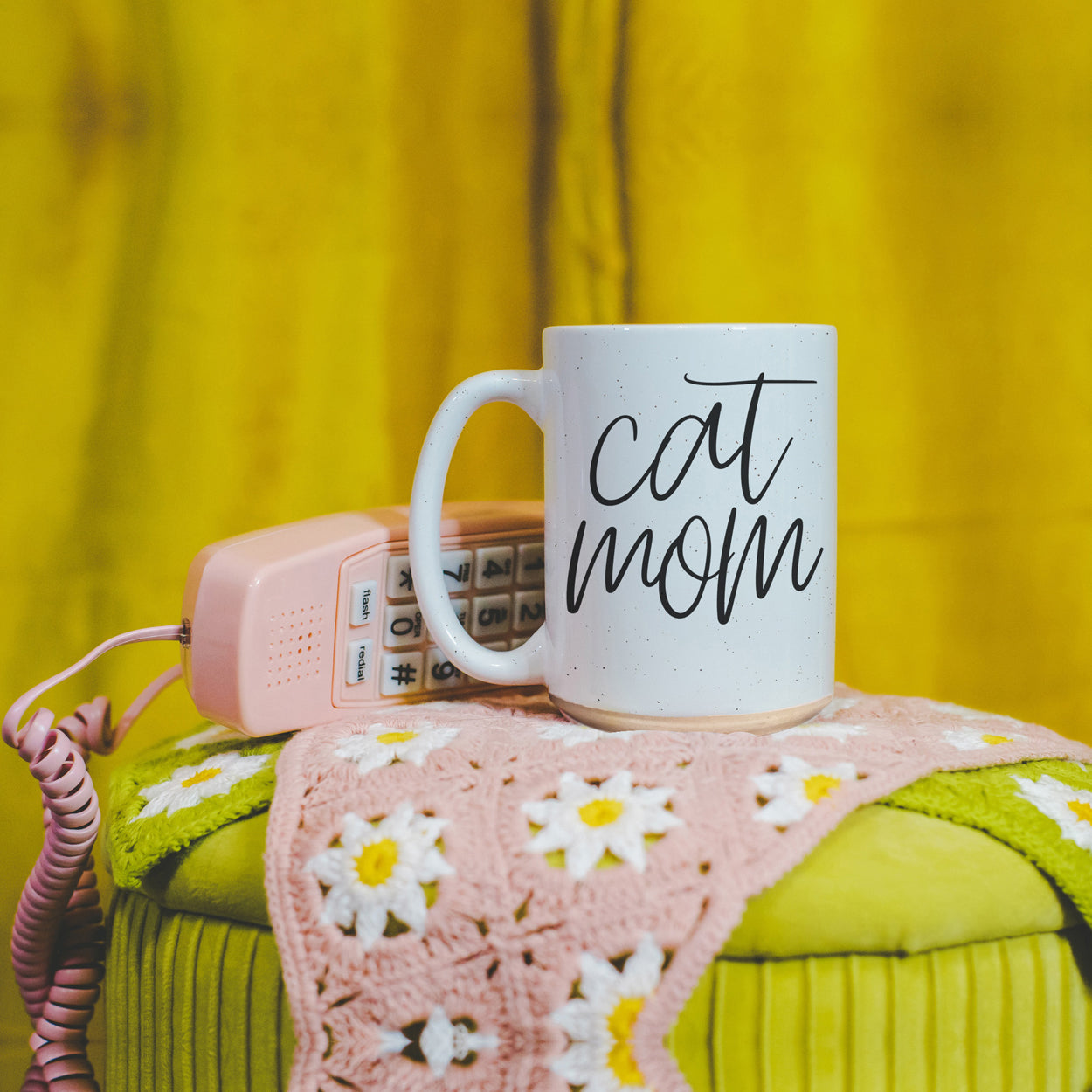 A stylish off-white ceramic mug with dark speckles, featuring a black graphic that reads 'Cat Mom' on both sides, perfect for cat lovers.