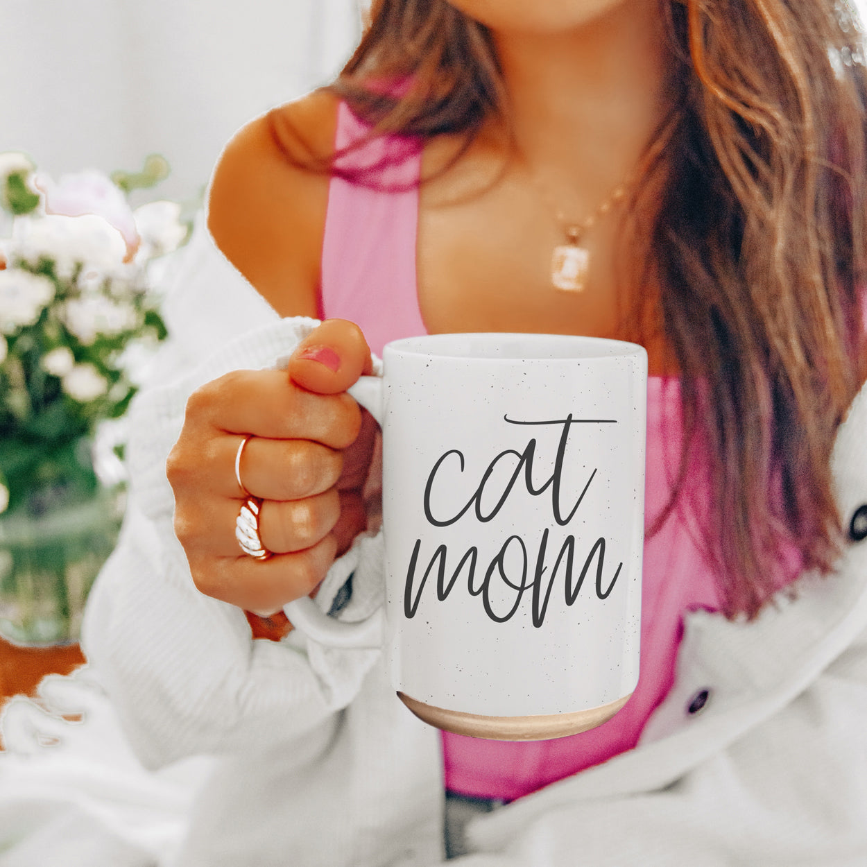 A stylish off-white ceramic mug with dark speckles, featuring a black graphic that reads 'Cat Mom' on both sides, perfect for cat lovers.