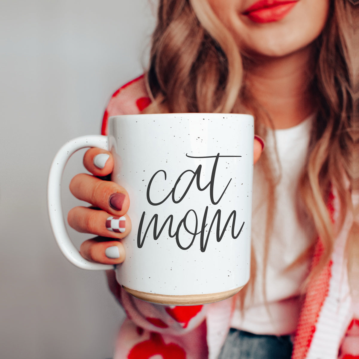 A stylish off-white ceramic mug with dark speckles, featuring a black graphic that reads 'Cat Mom' on both sides, perfect for cat lovers.