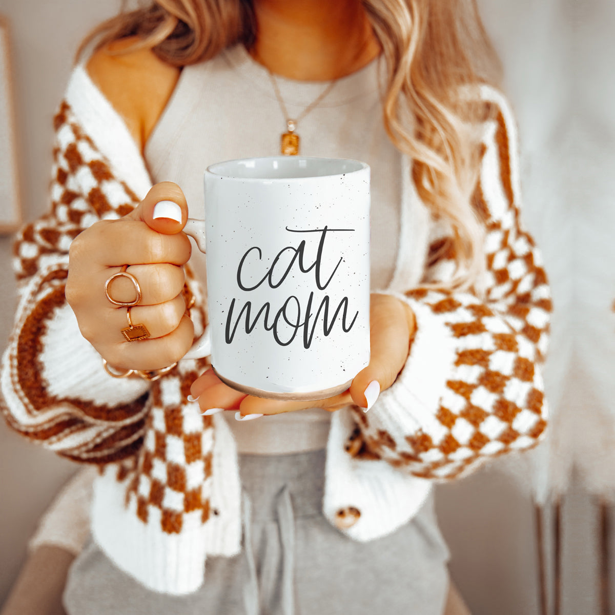 A stylish off-white ceramic mug with dark speckles, featuring a black graphic that reads 'Cat Mom' on both sides, perfect for cat lovers.